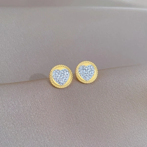 Close-up of golden heart earrings with sparkling crystals on textured satin background
