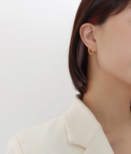 Detail of 18k gold plated heart stud earring with beaded texture on a model