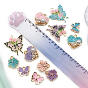 Detail view of colorful enamel butterfly and flower charms with scale ruler measurement