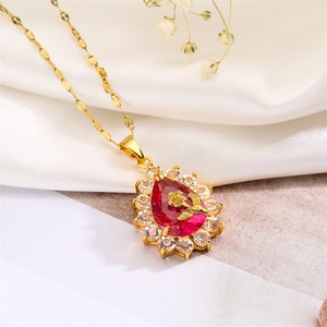 Macro detail of gold teardrop necklace with red gemstone and rose on white silk
