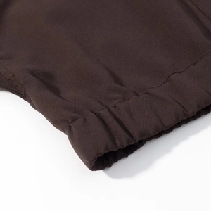 Detailed close-up of dark brown woven fabric with elastic cuff and reinforced stitching