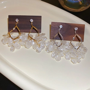Macro detail of petal-shaped tassel earrings with zircon studs and pearl finish petals