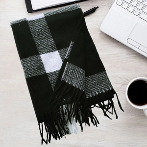 Detail of green and white plaid scarf with tassels on office desk with laptop