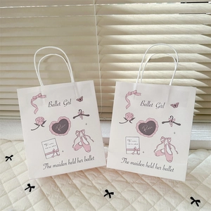 Detail view of white paper gift bags featuring pink ballet girl and floral illustrations