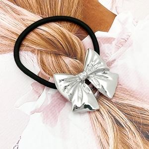 Close-up of a silver mirror-finish alloy bow hair tie with a black high-elasticity band