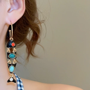 Detailed macro view of retro C-shaped fish tassel earrings with colorful enamel accents