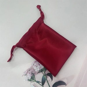 Detail of red satin drawstring bag with silk texture and pink carnation flowers