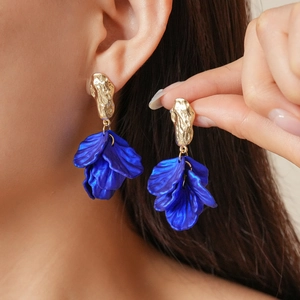 Detail of blue petal tassel earrings with golden hammered metal studs worn by model
