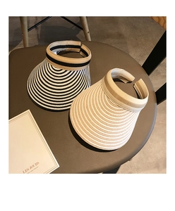 Close-up of striped straw sun visors with wide brims on a brown leather stool