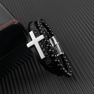 Detail of multi-layer black leather braid and silver cross on magnetic clasp bracelet