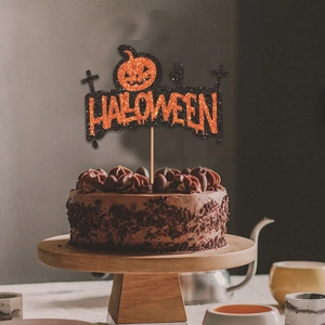 Halloween pumpkin cake topper with orange glitter lettering on a chocolate dessert