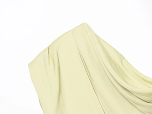 Detailed close-up of light green asymmetric top showing rich pleated fabric texture