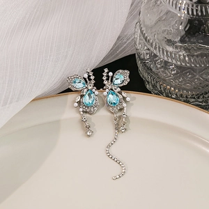 Detail of asymmetrical butterfly drop earrings with blue crystal and white pearls