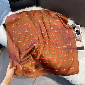 Détail d'un élégant foulard marron avec imprimés cerises sur une texture douce