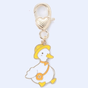 Close-up of cute cartoon white duck pendant with golden heart lobster clasp detail