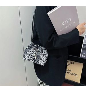 Detail of leopard print bucket bag with pearl handle and metal chain on black blazer