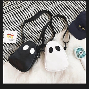 Detail showing quirky black and white ghost-shaped PU leather crossbody bags on a bed