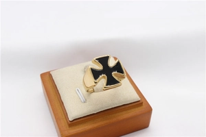 Macro detail of men's gold stainless steel ring with black cross inlay on wooden stand