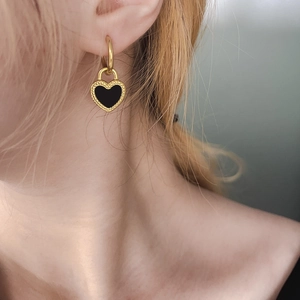 Elegante gouden vintage hart oorbellen met zwart email gedragen door een modemeisje