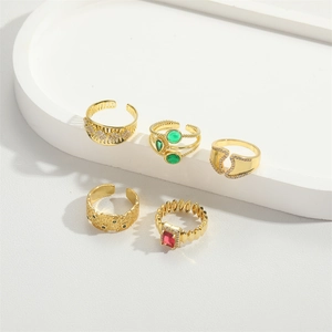 Set of 5 minimalist gold open rings with red and green zircons on a white tray