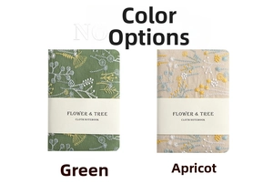 Close-up of linen fabric notebooks featuring green and beige floral tree embroidery