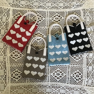 Knitted phone bags in red, blue, grey and black with heart pattern on lace cloth