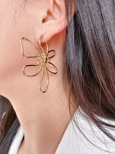 Detailed view of large gold metallic butterfly earring worn by a model in profile