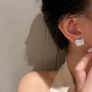 Détail de la texture froissée irrégulière sur la boucle d'oreille carrée argentée