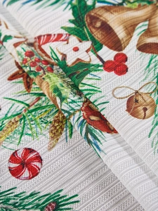 Detalle del mantel de Navidad con motivos de campanas, piñas y bayas festivas