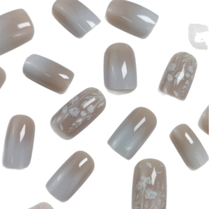 White gradient press-on nails with delicate floral patterns and glossy finish