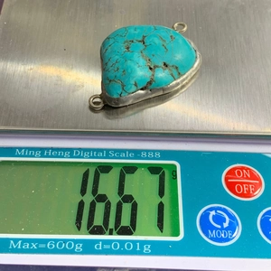 Macro shot of turquoise stone pendant on digital scale showing weight of 16.67 grams