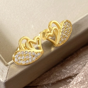 Macro shot of gold double-heart earrings with white cubic zirconia and hollow design