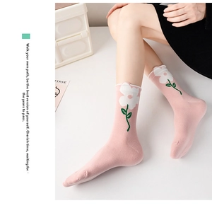 Detail of pink mid-calf socks with floral embroidery and elegant wavy ruffled cuffs