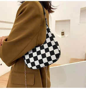 Detail of checkered crescent bag featuring black and white texture and gold chain strap