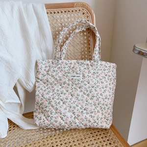 Quilted floral tote bag with pink flowers on a wicker chair in a lifestyle setting