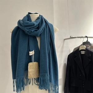 Detailed close-up of dark blue fringed scarf showing twill knit texture and brand tags