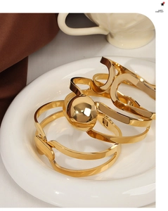 Macro view of geometric double-layered gold-plated titanium steel bangles on a ceramic plate