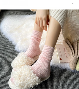 Close-up of pink ribbed knit wool socks worn with white shearling indoor slippers