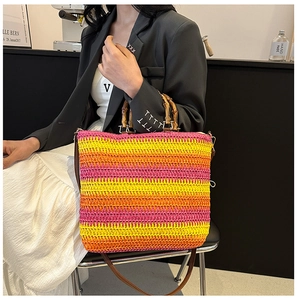Detail of hand-woven straw beach bag with pink stripes and bamboo handles