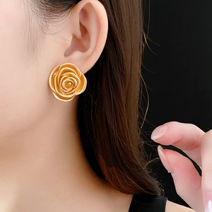 Close-up of a model wearing a vintage gold rose flower stud earring with delicate petals
