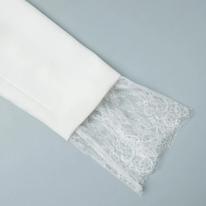 Detailed macro view of white blazer cuffs with intricate floral lace trim and eyelash edges