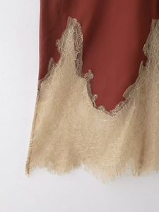 Detailed close-up of brick red satin hem with intricate beige gold lace trim edge