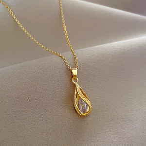 Elegant gold titanium steel teardrop necklace with crystal pendant on beige fabric