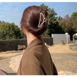 Close-up of a large pearl hair claw clip worn by a model for an elegant updo hairstyle