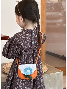 Rear view of child wearing orange crochet flower crossbody bag with white knit flap
