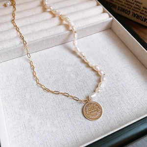 Detail of 14K gold plated coin pendant and freshwater pearl on a gold chain necklace