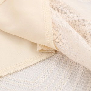 Close-up of beige sequin dress fabric showing fine lace mesh and high-quality stitching