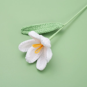 Handmade crochet white tulip with green stem on a soft green background