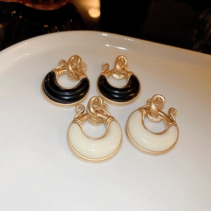 Macro shot of vintage resin C-shape hoop earrings in black and cream with gold metal studs