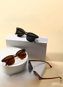 Clubmaster sunglasses displayed on white geometric plinths in black, brown and blue